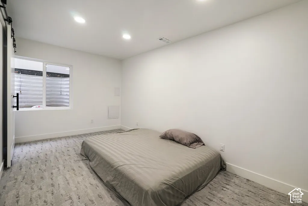 Neutral-toned wall-to-wall carpeting, recessed ceiling lighting, and a sliding barn-style door