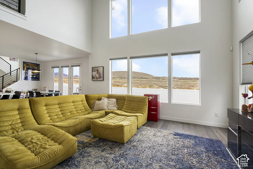 Double-height ceilings, expansive floor-to-ceiling windows, wood-finish flooring, and a metal stair railing with horizontal balusters
