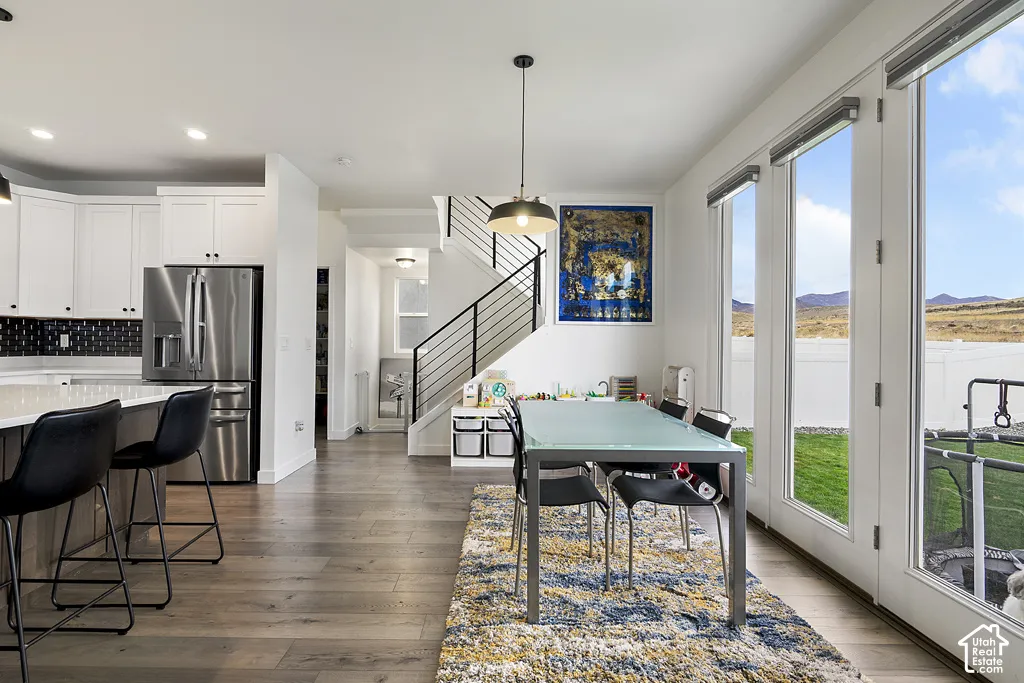 Kitchen featuring stainless steel appliances, white cabinetry, a center island, wood-finish flooring, and a staircase with metal railing