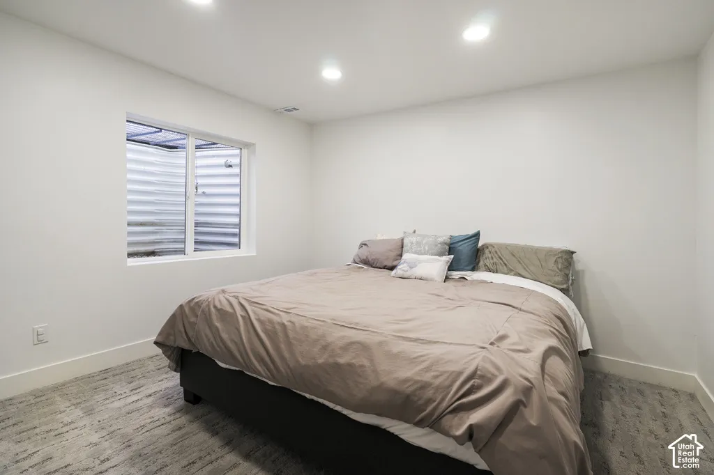 Neutral-toned carpeting, recessed ceiling lighting, and a window with a corrugated metal window well