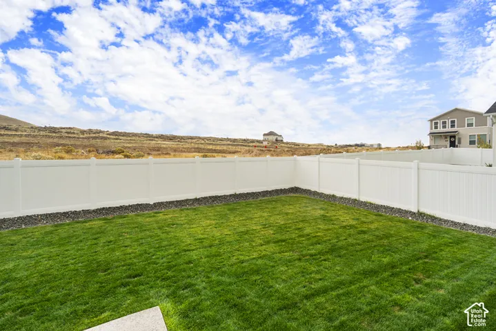 Fenced backyard featuring a manicured lawn, stone aggregate border, and mountain horizon