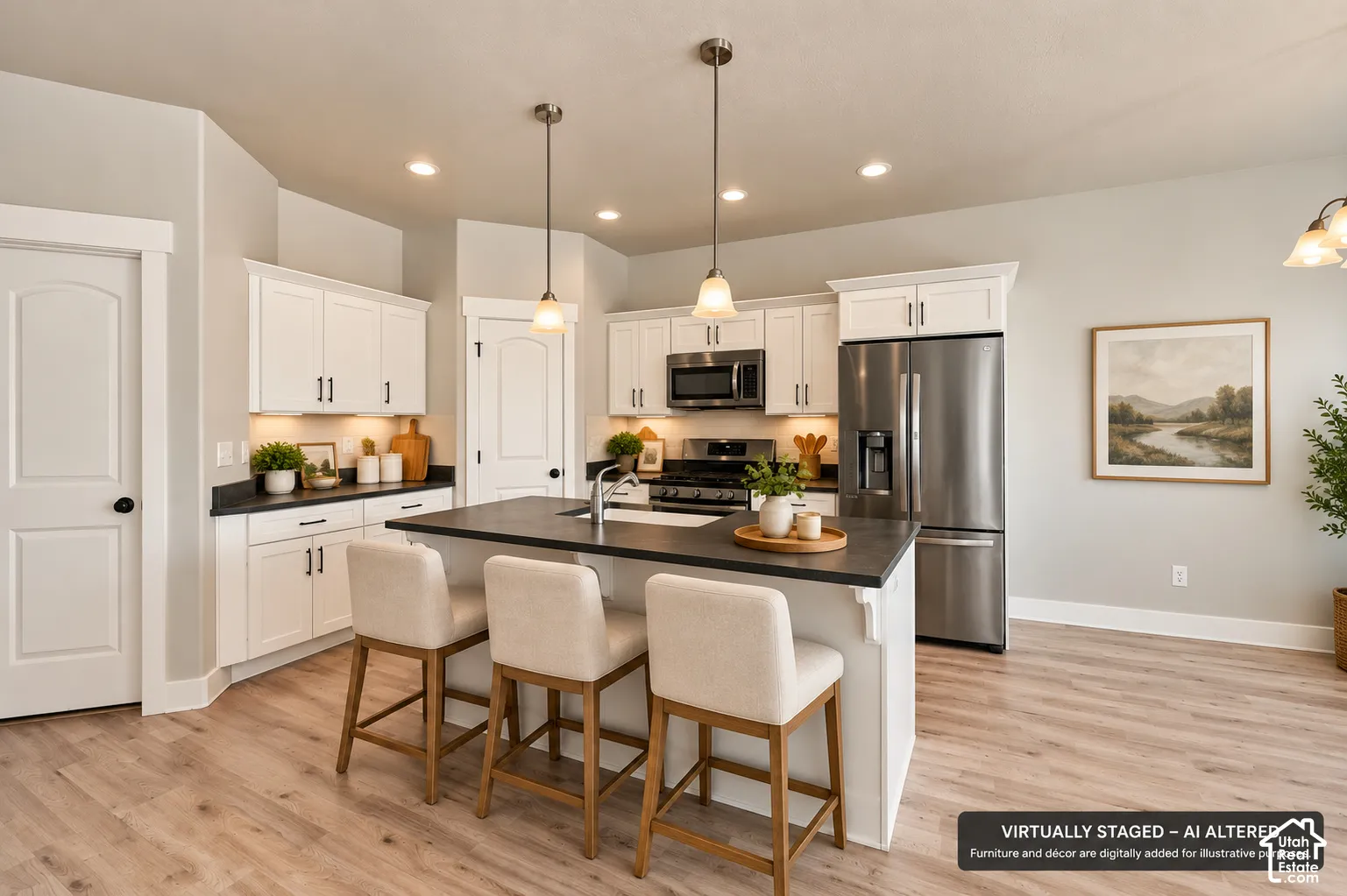 Kitchen featuring white cabinetry, dark countertops, a center island with an integrated sink, stainless steel appliances, and wood-finish flooring