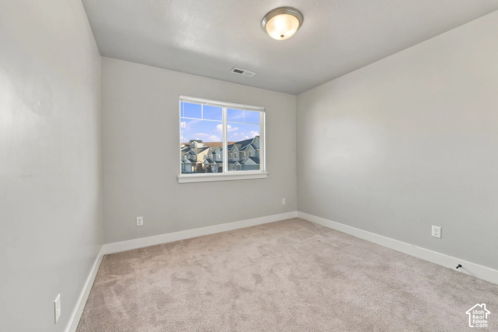Neutral-toned walls, wall-to-wall carpeting, single-pane window with white frame, and flush-mount overhead lighting
