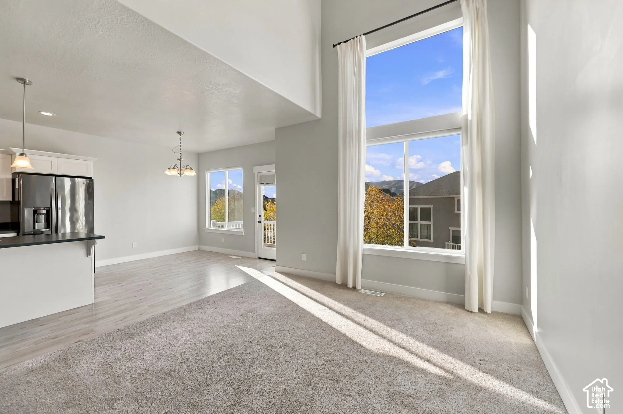 Double-height ceilings, floor-to-ceiling windows, stainless steel kitchen appliances, wood-finish flooring, and pendant lighting