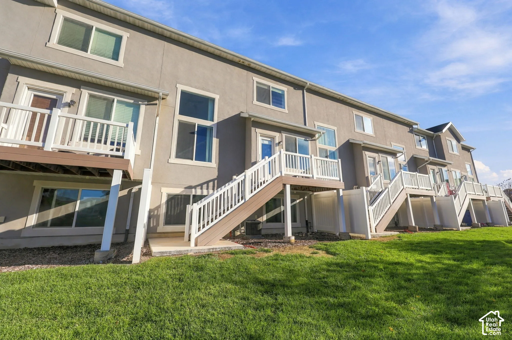 Exterior elevation featuring stucco siding, elevated wood-tone decks with white railings, and sliding glass door access
