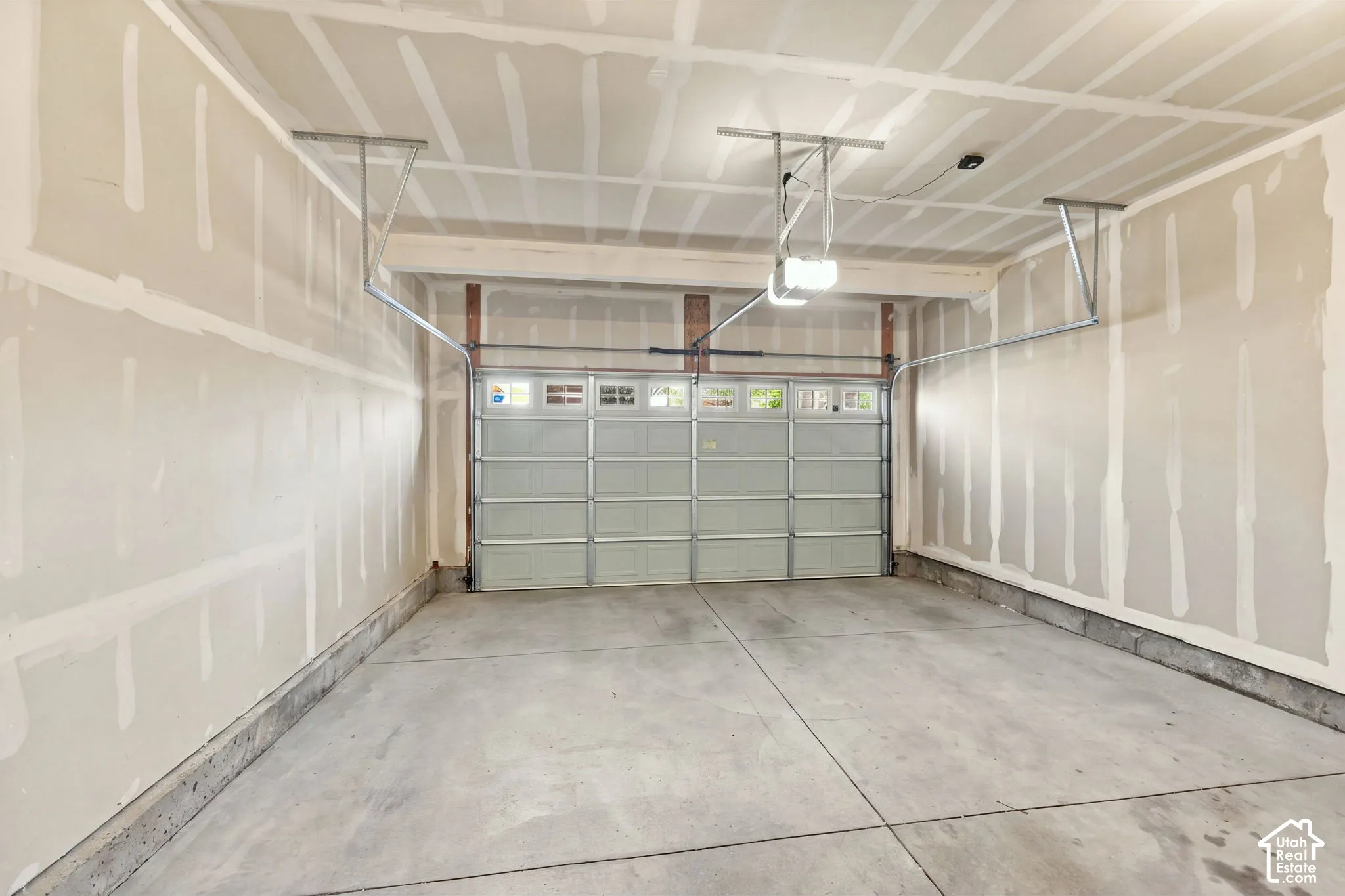 Multi-car garage featuring a concrete floor, metal roll-up door with windows, and ceiling-mounted garage door opener