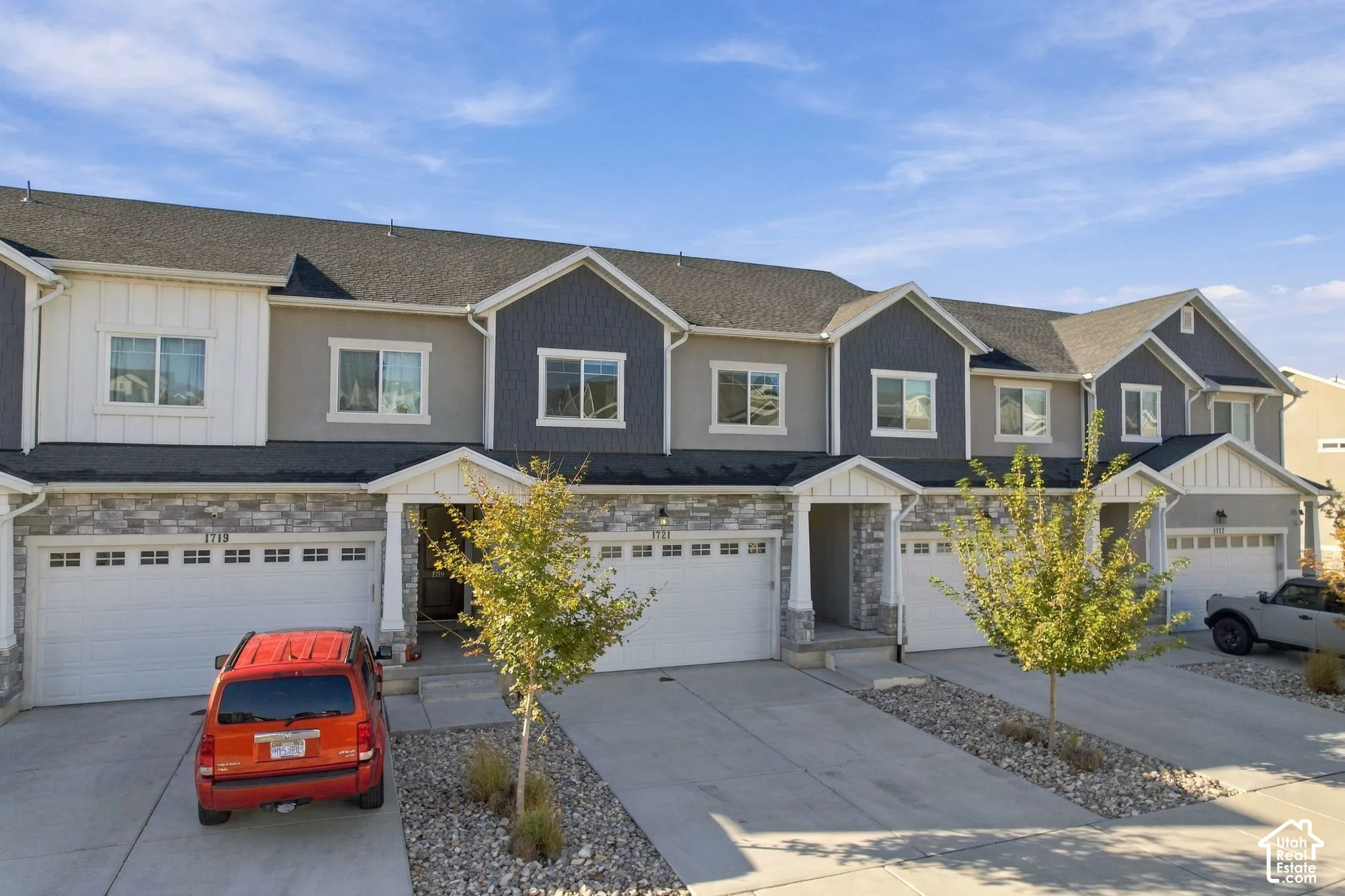 Multi-unit residential exterior featuring horizontal lap siding, vertical board-and-batten accents, stone veneer lower facades, and integrated multi-car garages