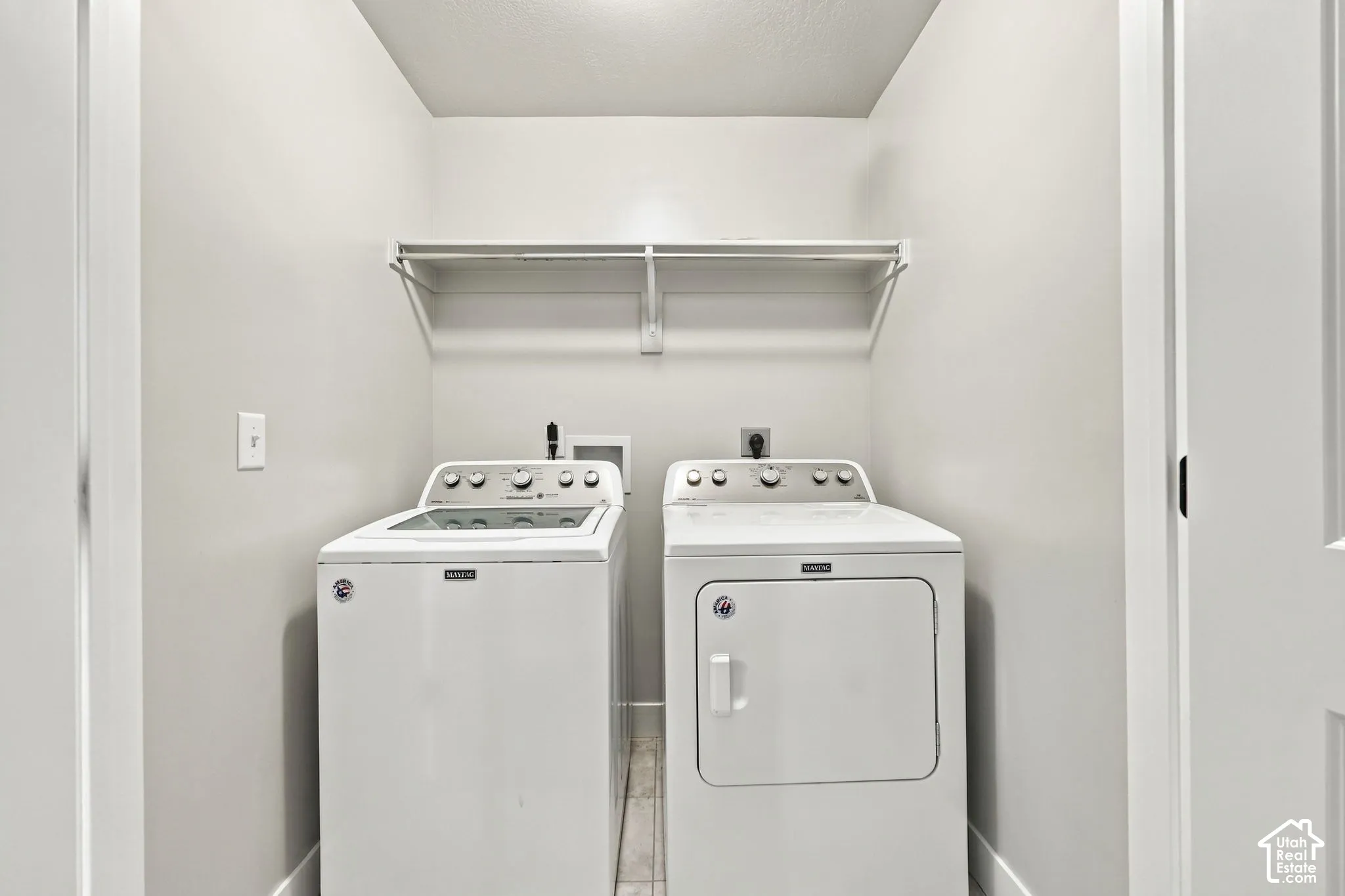 Utility space featuring neutral wall tones, tile flooring, and a built-in overhead wire storage shelf