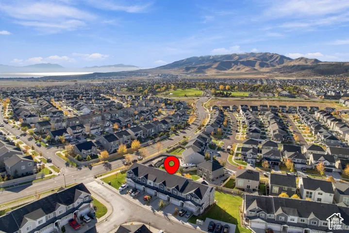 Aerial perspective of a multi-unit residential structure featuring a multi-gabled roofline, asphalt shingles, and proximity to mountain range and regional landscape