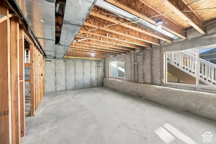 Unfinished lower level featuring exposed wood joist ceilings, poured concrete flooring, insulated foundation walls, and multiple dual-pane windows