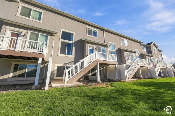 Exterior elevation featuring stucco siding, elevated wood-tone decks with white railings, and sliding glass door access