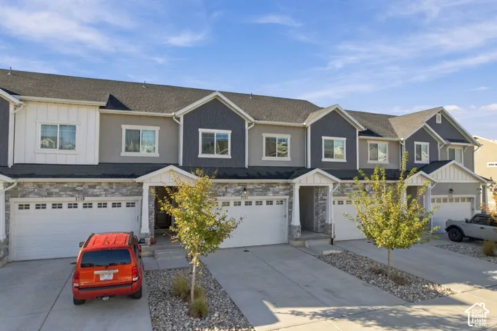 Multi-unit residential exterior featuring horizontal lap siding, vertical board-and-batten accents, stone veneer lower facades, and integrated multi-car garages
