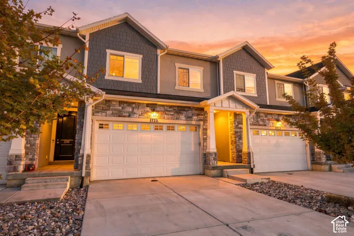 Multi-level exterior featuring a stone veneer facade, shake-style siding, gabled rooflines, covered entryway, and attached multi-car garages
