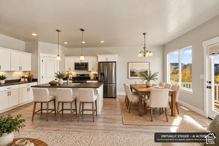 Kitchen featuring white cabinetry, dark countertops, an island with pendant lighting, stainless steel appliances, and wood-finish flooring