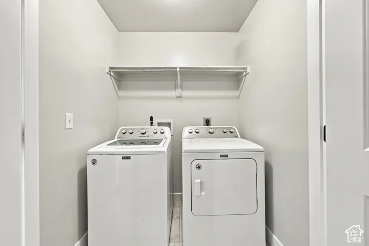 Utility space featuring neutral wall tones, tile flooring, and a built-in overhead wire storage shelf