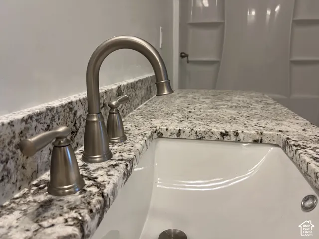 Stone countertop with an integrated undermount sink, brushed nickel widespread faucet, and multi-piece molded surround