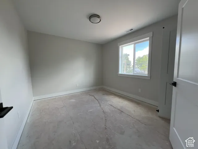 Neutral-toned room featuring a single-pane sliding window, white interior door with matte black hardware, and a flush-mount ceiling light fixture