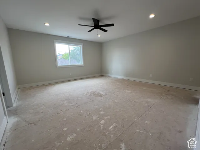Spacious room featuring neutral wall paint, recessed lighting, a matte black ceiling fan, and a single-pane sliding window