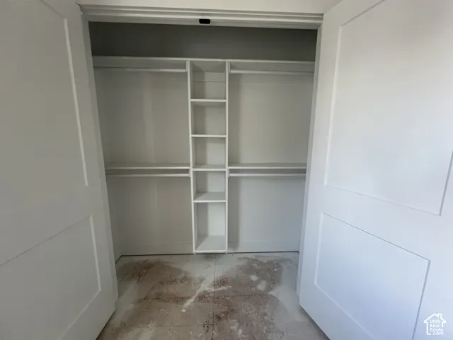 Custom built-in white closet organization system featuring dual-level hanging rods and integrated vertical shelving