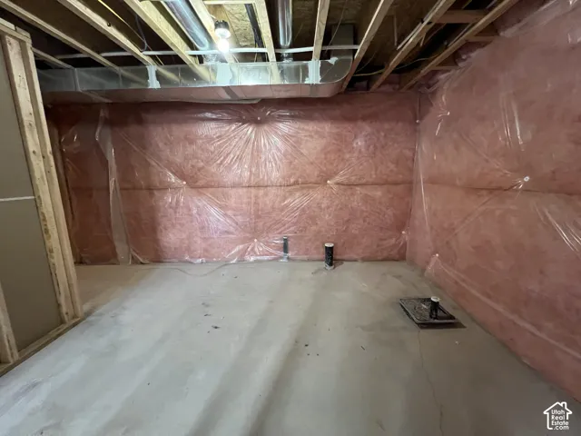 Unfinished space with exposed wood ceiling joists, concrete flooring, pink fiberglass wall insulation, and visible plumbing rough-ins