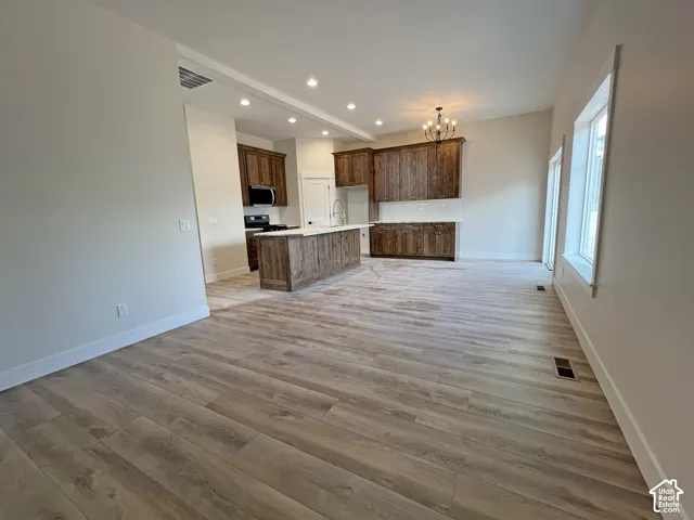Open-concept kitchen featuring dark wood cabinetry, a central island with a stone-top surface, recessed lighting, and wood-finish flooring