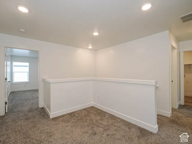 Neutral-toned carpeting, recessed ceiling lighting, and crisp white wall finishes