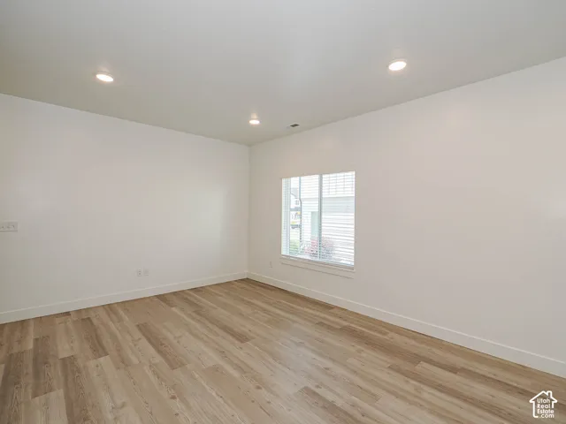 Neutral-toned interior space featuring wood-finish flooring, recessed lighting, and a single-pane window