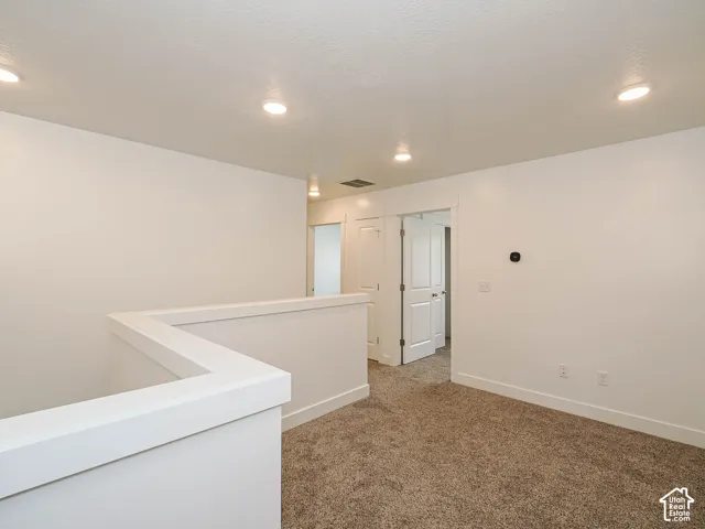 Neutral-toned wall-to-wall carpeting, recessed ceiling lighting, and solid-core interior doors with paneled detailing