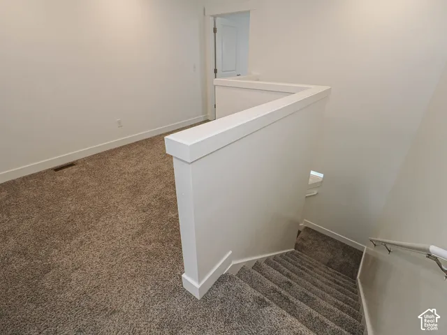 Neutral wall-to-wall carpeting, crisp white wall finishes, solid-panel interior door, and a clean-lined half wall featuring a white cap railing