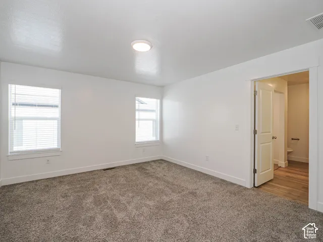 Neutral interior space featuring carpeted flooring, two dual-pane windows, and a solid-core interior door