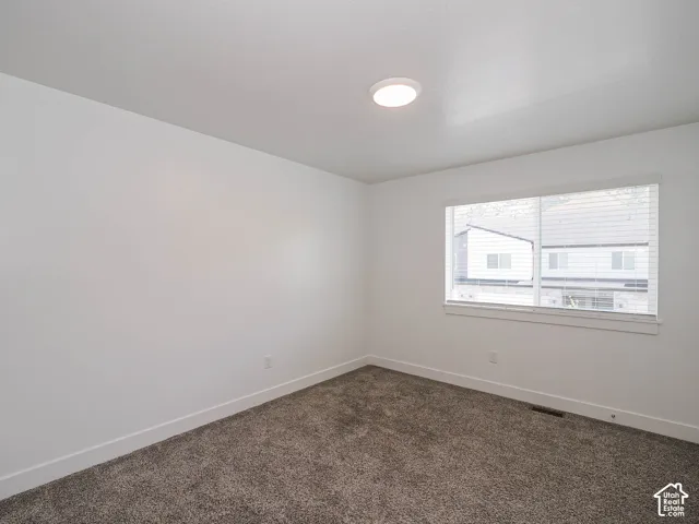 Neutral interior space featuring textured carpeting, white walls, a flush-mount ceiling light, and a horizontal sliding window