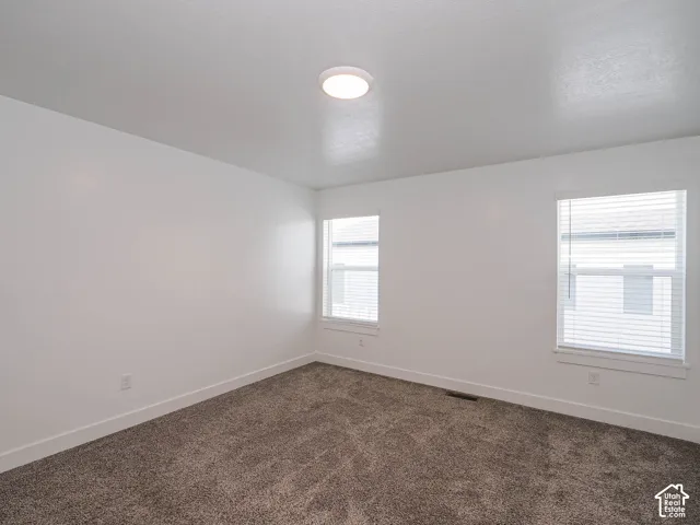 Neutral-toned carpeting, crisp white walls, dual windows with integrated horizontal blinds, and a flush-mount circular ceiling light