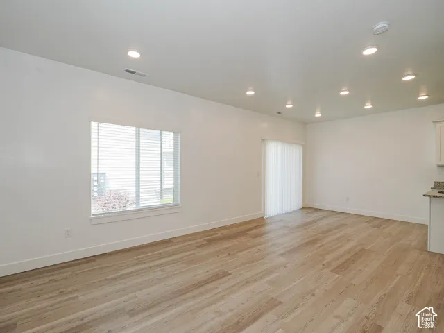 Wood-finish flooring, recessed lighting, neutral wall palette, single-hung window, and sliding glass door