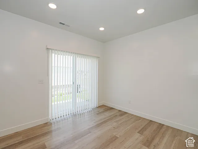 Interior space featuring wood-finish flooring, recessed lighting, and sliding glass doors with vertical blinds