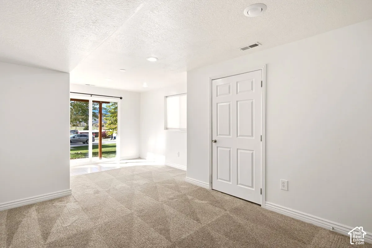 Neutral-toned carpeting, white walls, six-panel interior door, and sliding glass door with external exposure