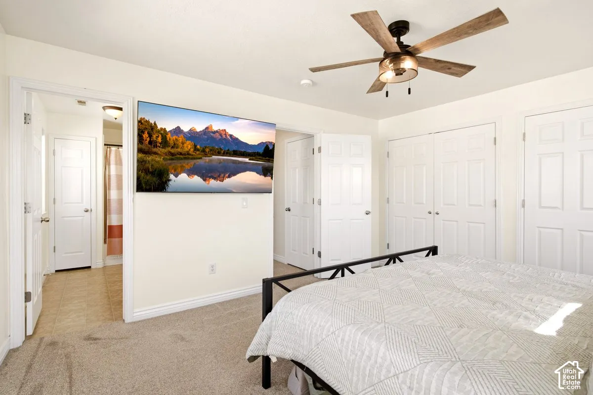 Neutral-toned carpeted flooring, ceiling fan with wood-finish blades, and multiple paneled interior doors