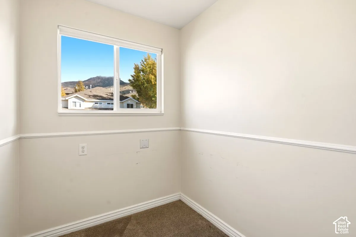 Neutral-toned room featuring carpeting, chair rail molding, and a sliding window with mountain scenery