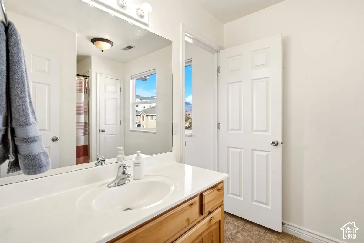 Bathroom featuring a natural wood-finish vanity with a seamless integrated sink, a single-handle chrome faucet, a wall-to-wall mirror, and multi-panel interior doors