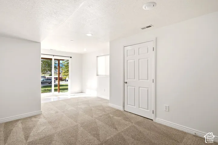 Neutral-toned carpeting, white walls, six-panel interior door, and sliding glass door with external exposure