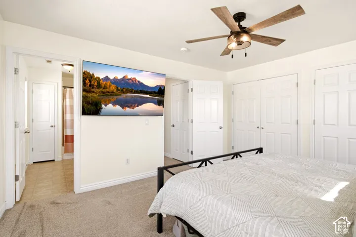 Neutral-toned carpeted flooring, ceiling fan with wood-finish blades, and multiple paneled interior doors