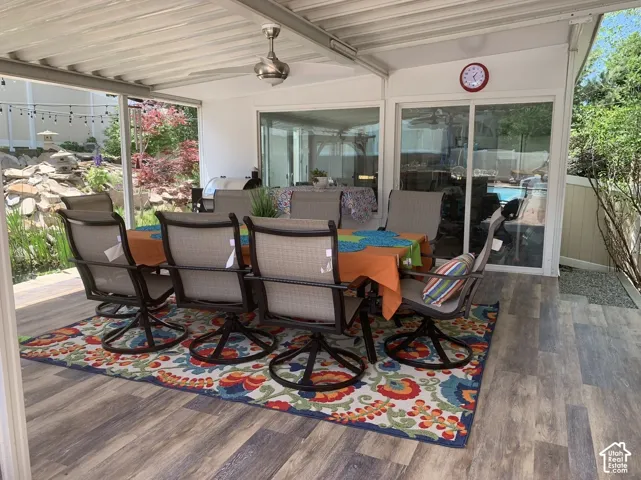 Covered patio featuring wood-finish flooring, a ceiling fan, sliding glass doors, and a decorative rock garden