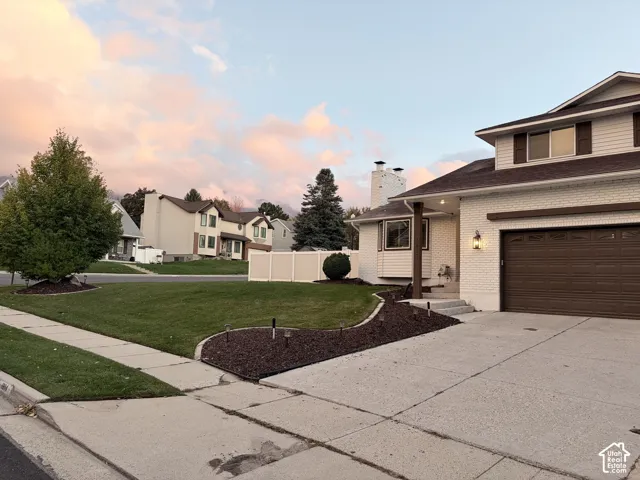Multi-level exterior featuring white painted brick masonry, horizontal siding, a two-car garage, and a concrete driveway
