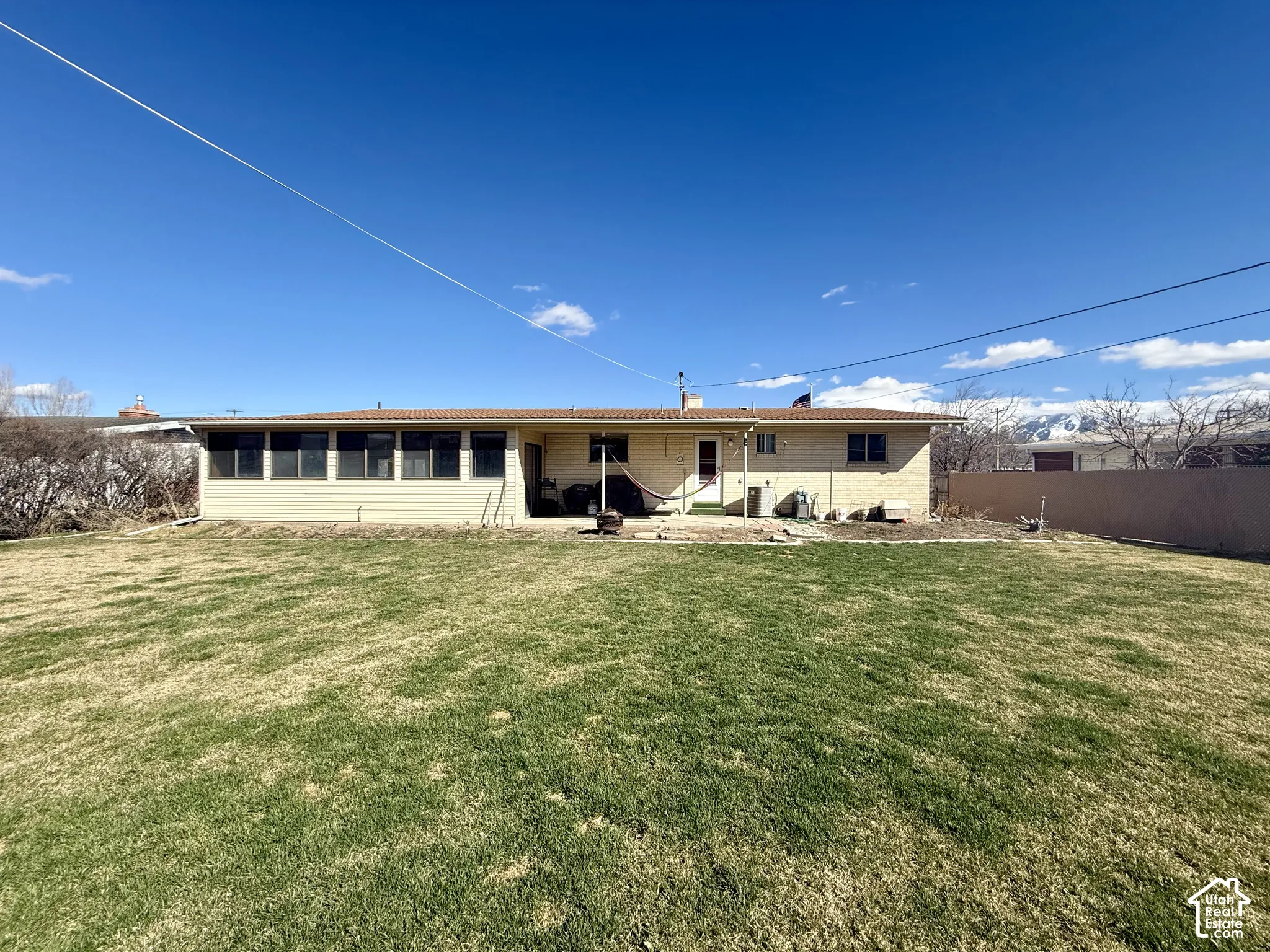 Expansive backyard featuring a large grass lawn, solid-surface perimeter fencing, and mountain backdrop.