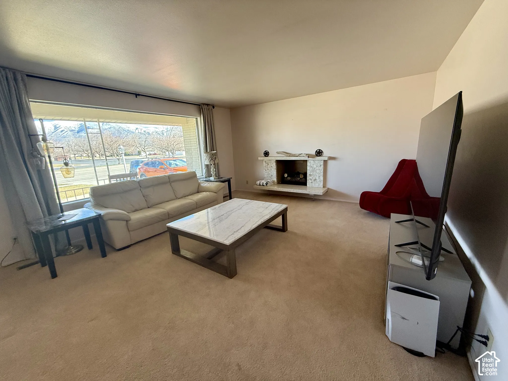 Living area featuring a floor-to-ceiling picture window and afireplace with a textured stone facade and hearth