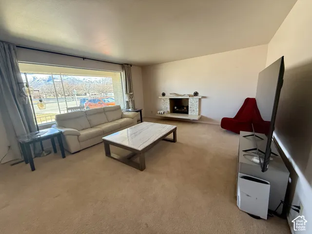 Living area featuring a floor-to-ceiling picture window and afireplace with a textured stone facade and hearth
