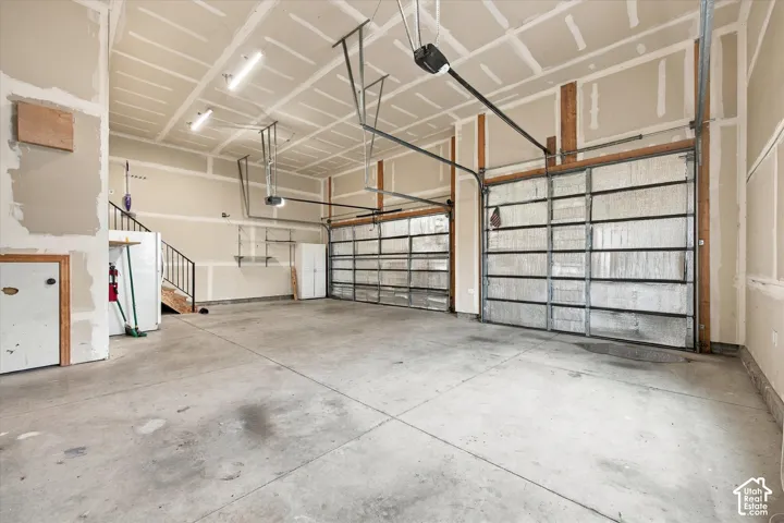 Multi-car garage featuring a concrete floor, high ceilings with mounted LED lighting, and two sectional roll-up garage doors
