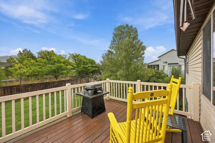 Elevated deck with wood-finish decking and perimeter railing, featuring a grassy backyard and wood fencing