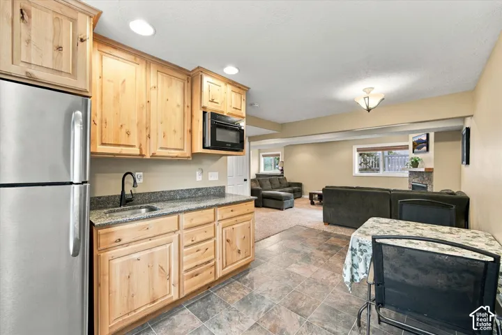 Kitchenette featuring natural wood cabinetry, stone-finish countertops, stainless steel refrigerator, built-in microwave, and recessed lighting