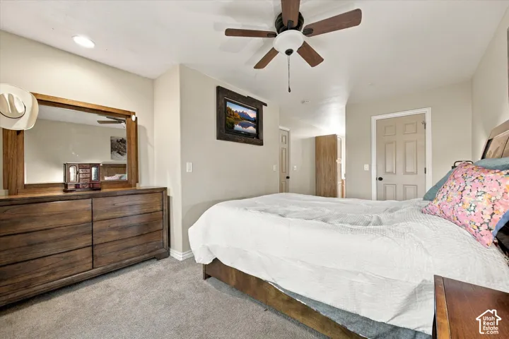 Neutral-toned bedroom featuring carpeting, a multi-blade ceiling fan, and a six-panel interior door