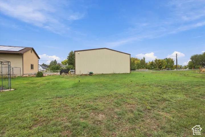 Expansive parcel featuring a detached metal structure, ground-mounted solar panels, and mature trees